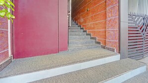 A staircase with a red wall and a metal railing. - Fabhotel Pk Residency (Ernakulam)