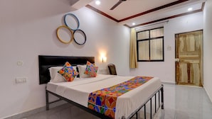 A bedroom with a bed, a ceiling fan, a window with curtains, and a door. - Fabhotel Zelosena (Calangute)