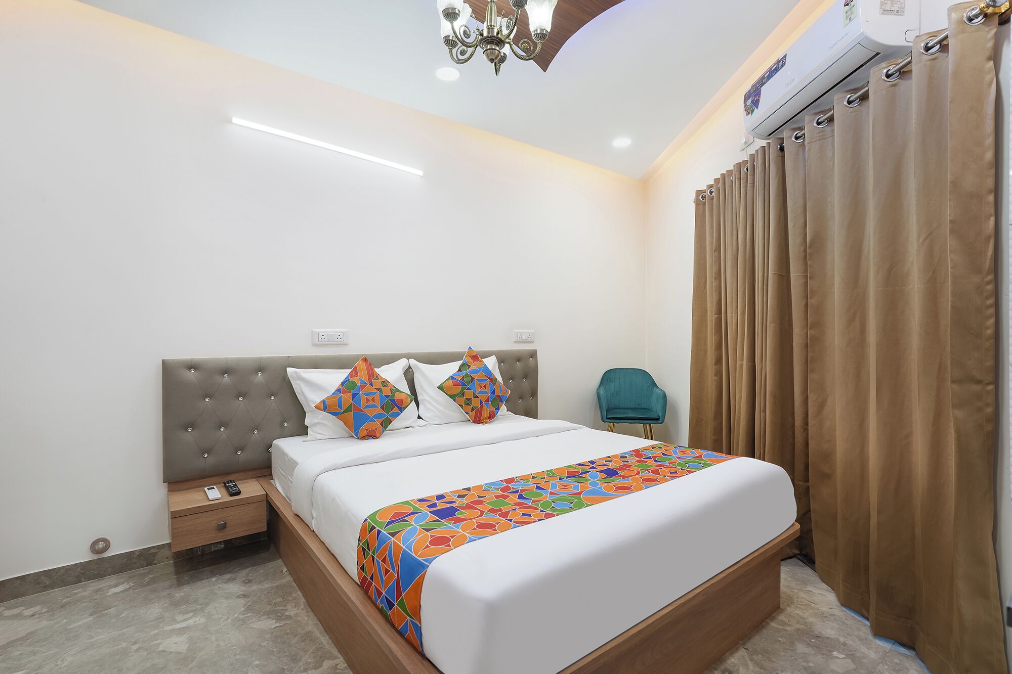 Habitación de hotel con una cama grande, una mesita de noche, una silla, una lámpara de techo y un equipo de aire acondicionado.