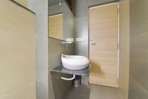 Un baño pequeño con un lavamanos blanco, un espejo y una puerta de madera.