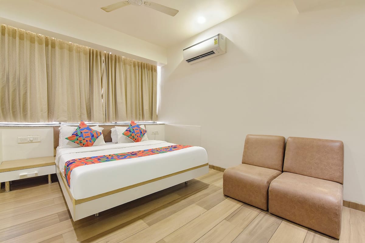 Ein Hotelzimmer mit einem Bett, einem Nachttisch, einem Sessel und einer Klimaanlage.