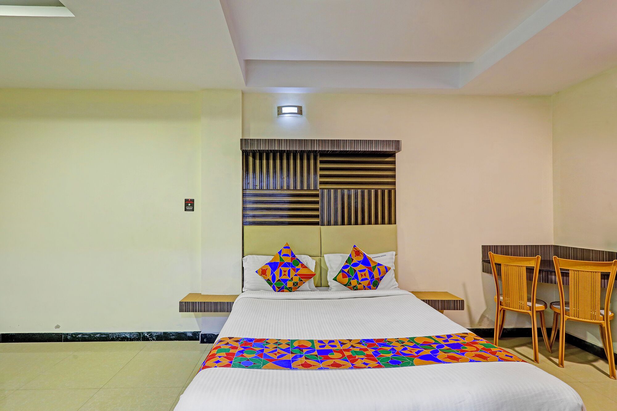 Una habitación de hotel con una cama, dos mesitas de noche, un escritorio y una silla.