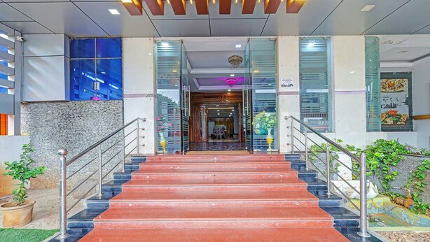 A staircase leading to a lobby with a stone wall, glass doors, and a chandelier. - Fabhotel Yagna Residency (Puducherry)