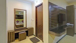 A hallway with a mirror, a door, and a modern bathroom with a striped wall and a sink. - Fabhotel Yagna Residency (Puducherry)
