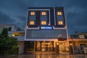 Un hotel moderno con un llamativo letrero de 'fab hotels', entrada de vidrio y fachada bien iluminada.