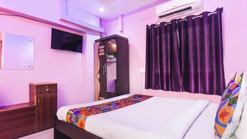 A bedroom with a bed, a wardrobe, a TV, an air conditioner, and purple curtains.