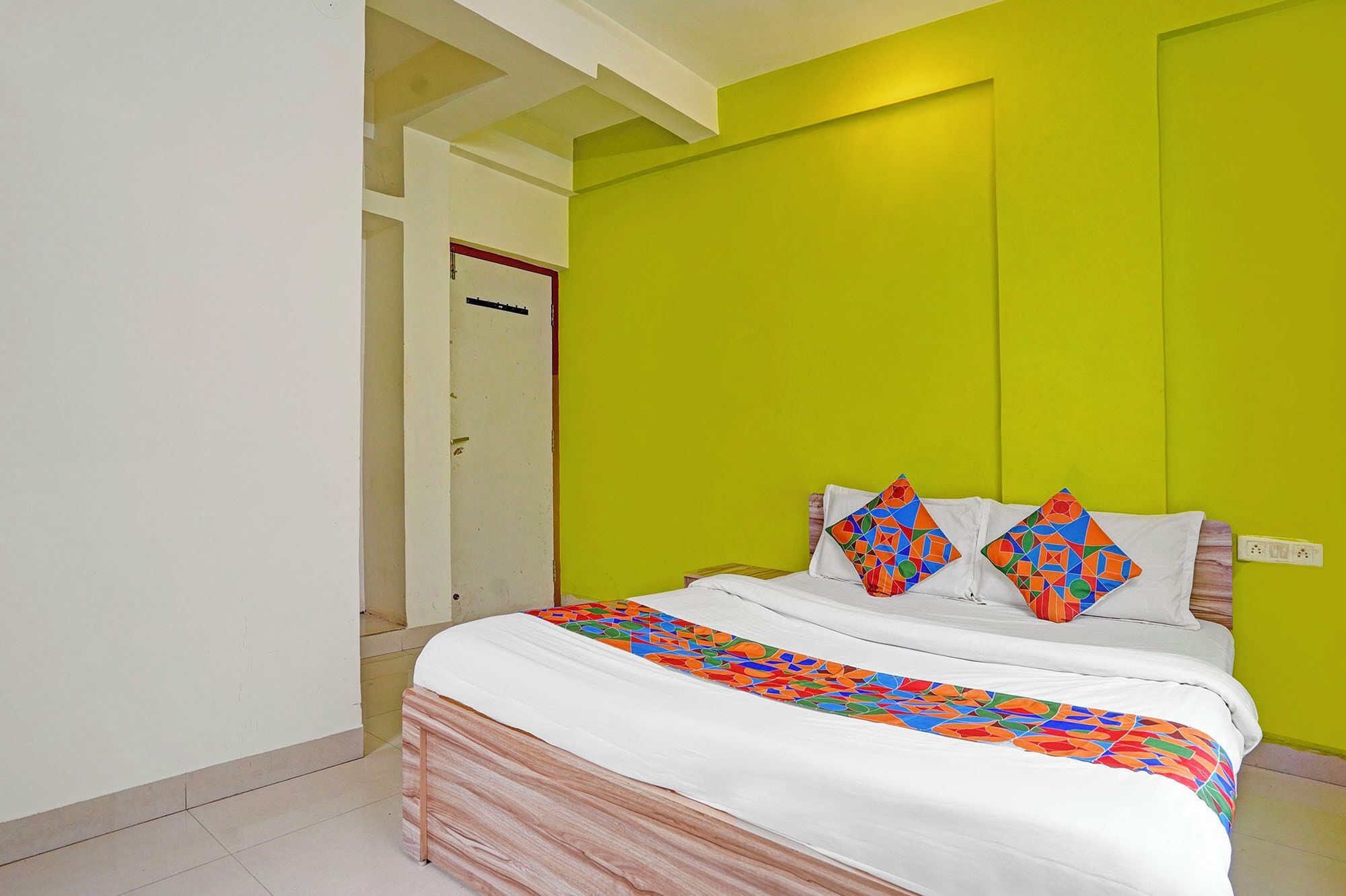 A bedroom with a bed, a bright green wall, and a white door.
