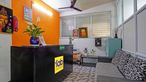 Un espace d’accueil avec un bureau noir, un panneau d’identification pour la réception, un calendrier et une statue de Bouddha.