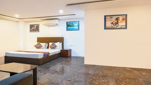 A modern hotel room with a bed, a small table, and a nightstand. There are two framed pictures on the wall. - Fabhotel Wild Wings Kothapet (Hyderabad)