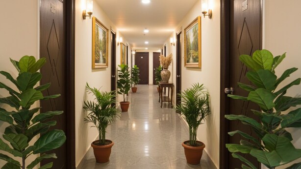 A hotel hallway with doors on both sides, potted plants, and framed pictures on the walls. - Fabhotel Wild Wings Kothapet (Hyderabad)
