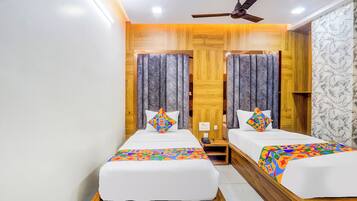 Habitación de hotel con dos camas, cabeceros de madera, ventilador de techo y pared con diseño de mármol.