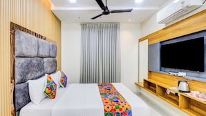 Una habitación de hotel moderna con una cama grande, un televisor de pantalla plana y un ventilador de techo.