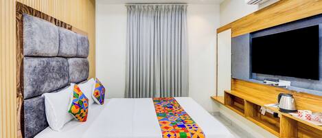 A modern hotel room with a large bed, a flat-screen TV, and a ceiling fan.