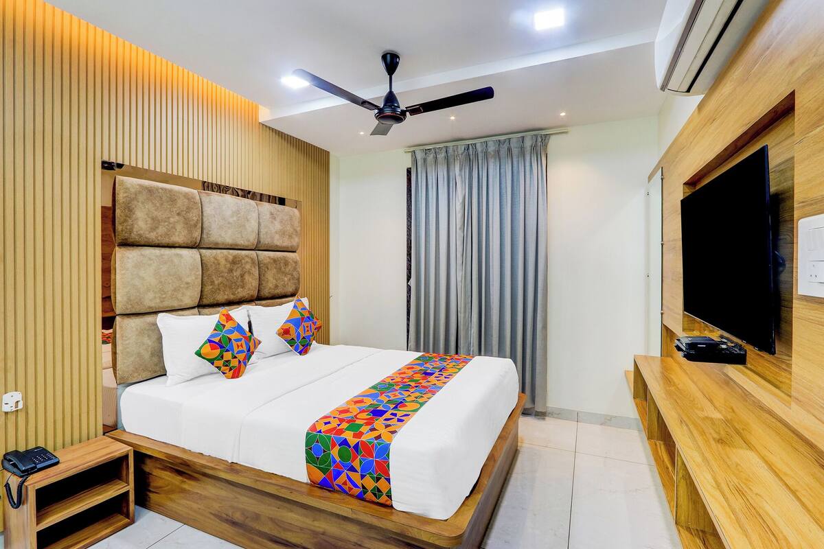 Une chambre d’hôtel moderne avec un grand lit, un ventilateur de plafond, une télévision et un meuble en bois pour la télévision.