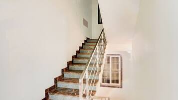 A staircase with a metal railing and a window with bars.