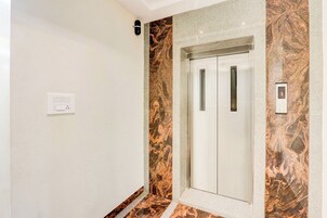 Un ascensor con pared de mármol y una pantalla digital que muestra el número del piso.
