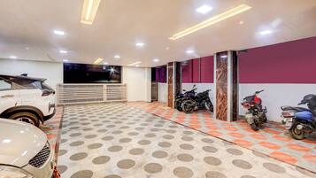 A parking garage with a white car and several motorcycles.