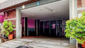 Entrada de hotel con diseño moderno, destacando un revestimiento de mármol, un techo de madera y plantas en macetas.