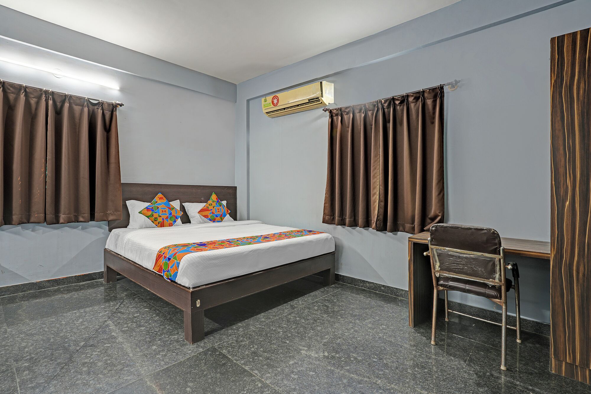 A hotel room with a bed, a desk, and curtains.