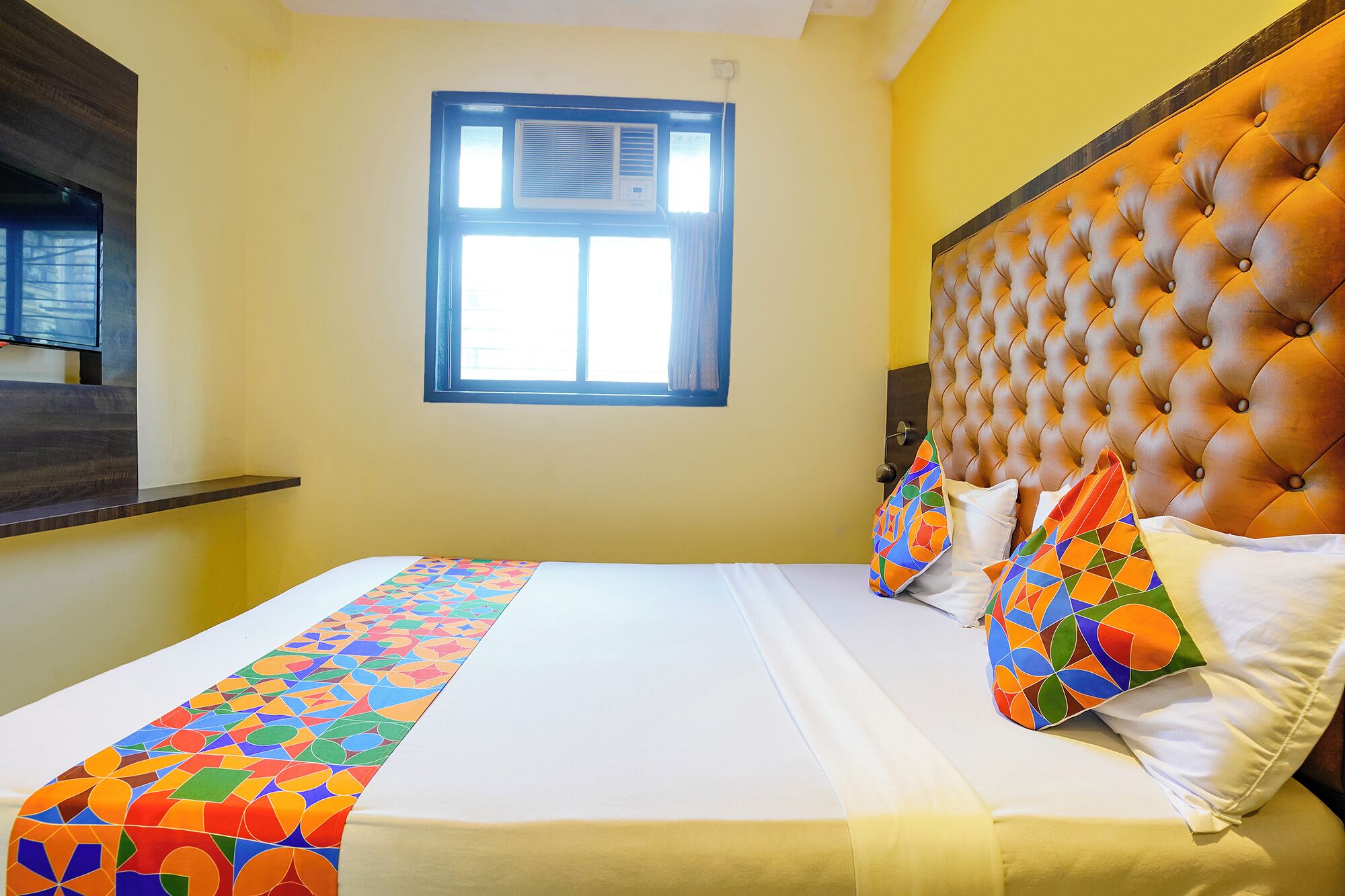 Ein Hotelzimmer mit Bett, Fenster und Fernseher an der Wand.
