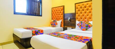 A hotel room with two beds, each with a colorful geometric-patterned bedspread.