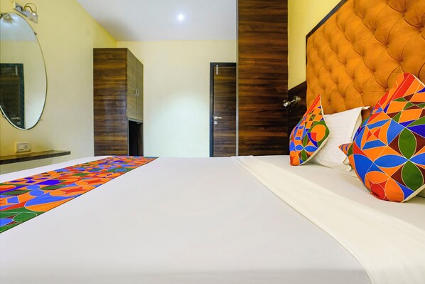 A bedroom with a bed, a mirror, and a door.