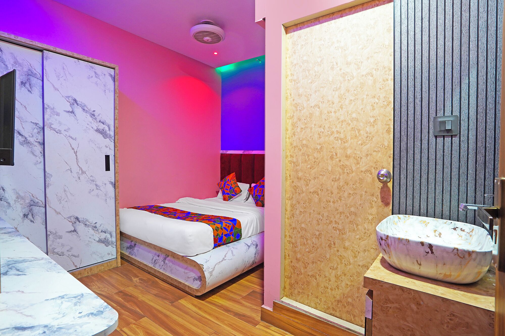 Une chambre à coucher avec un lit, une coiffeuse avec un lavabo et une porte donnant sur un mur à texture.