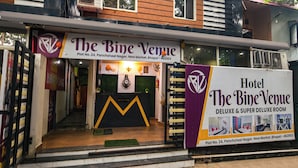 The Bine Venue hotel entrance with a reception desk, a staircase leading inside, and a banner advertising Deluxe & Super Deluxe rooms. - Fabhotel Bine Venue (Bhopal)