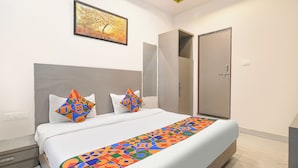 A bedroom with a bed, two pillows, a colorful rug, a painting, and a wardrobe. - Fabhotel Bine Venue (Bhopal)