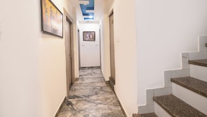 A hallway with marble flooring, white walls, and a blue ceiling. There are two doors and a staircase on the right. - Fabhotel Bine Venue (Bhopal)