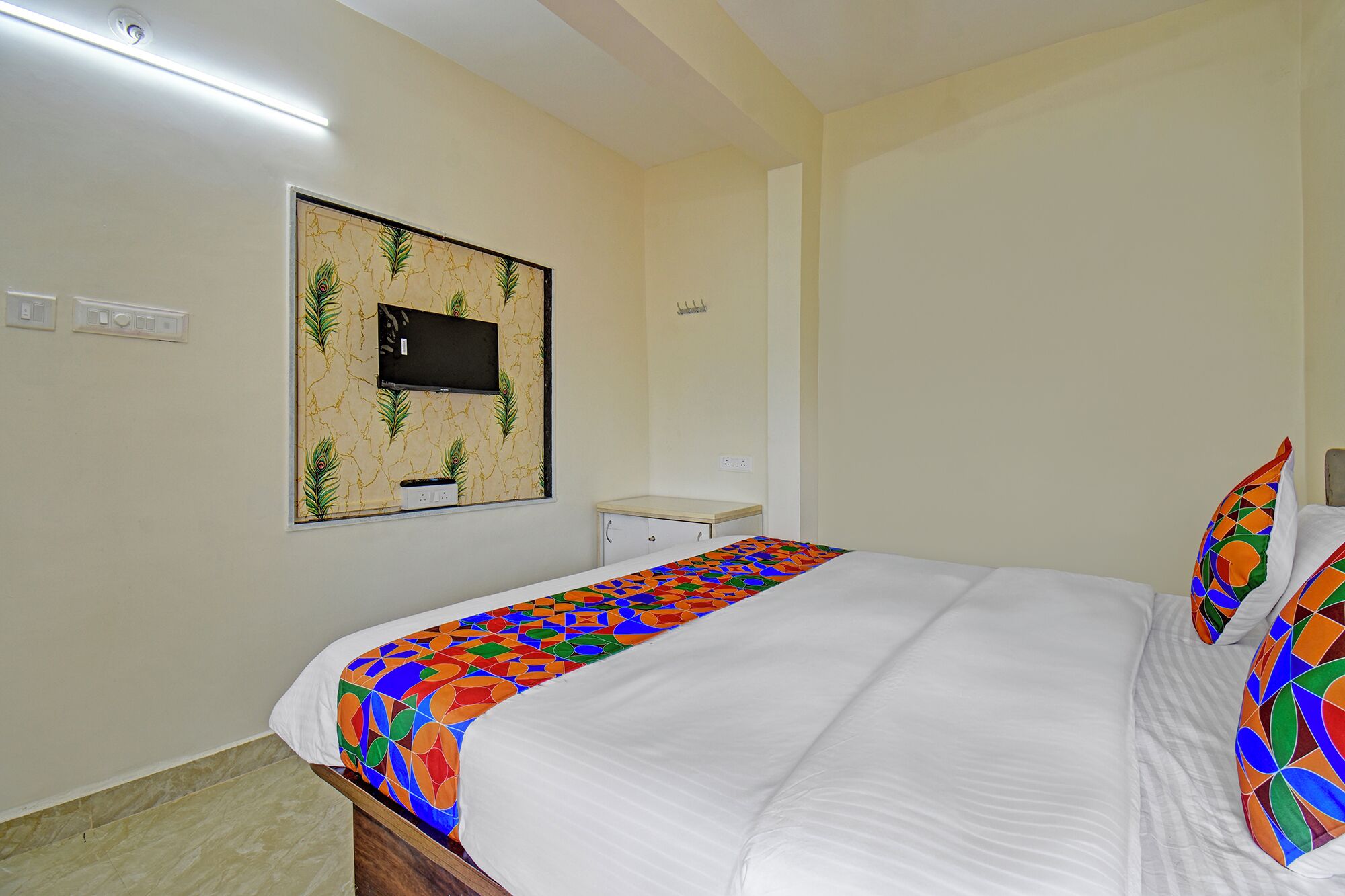 A bedroom with a bed, a small desk, and a wall-mounted TV.