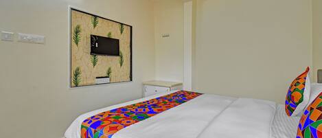 A bedroom with a bed, a small desk, and a wall-mounted TV.