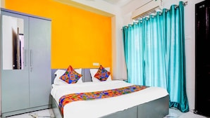 A bedroom with a bed, a wardrobe, a bathroom door, and a curtain. - FabHotel Lotus Prime Stay (Paud)