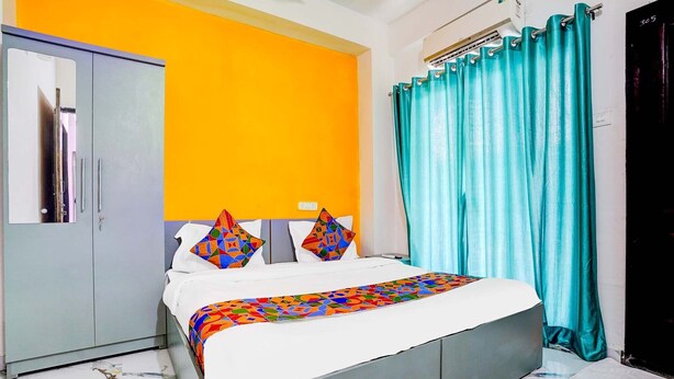 A bedroom with a bed, a wardrobe, a bathroom door, and a curtain. - FabHotel Lotus Prime Stay - Hinjawadi (Paud)