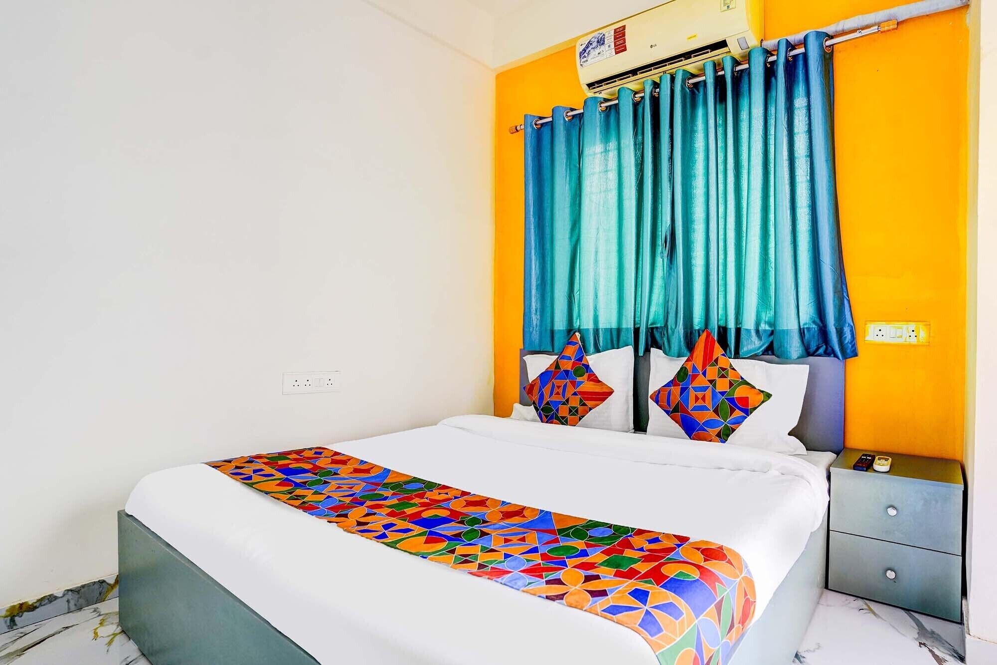 A bedroom with a bed, a nightstand, a wall-mounted air conditioner, and a window with teal curtains.