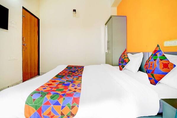 A hotel room with a bed, a wooden door, and a wall with a light switch.