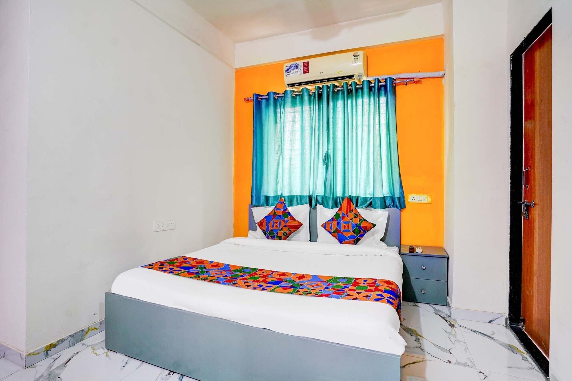 A bedroom with a bed, a window with curtains, an air conditioning unit, and a door.