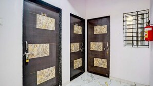 A hallway with three dark wooden doors, each with a numbered plaque. A fire extinguisher is mounted on the wall to the right. - FabHotel Lotus Prime Stay (Paud)