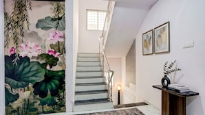 A staircase with a railing, a wall-mounted light, and a framed botanical print. - FabHotel Lotus Prime Stay (Paud)