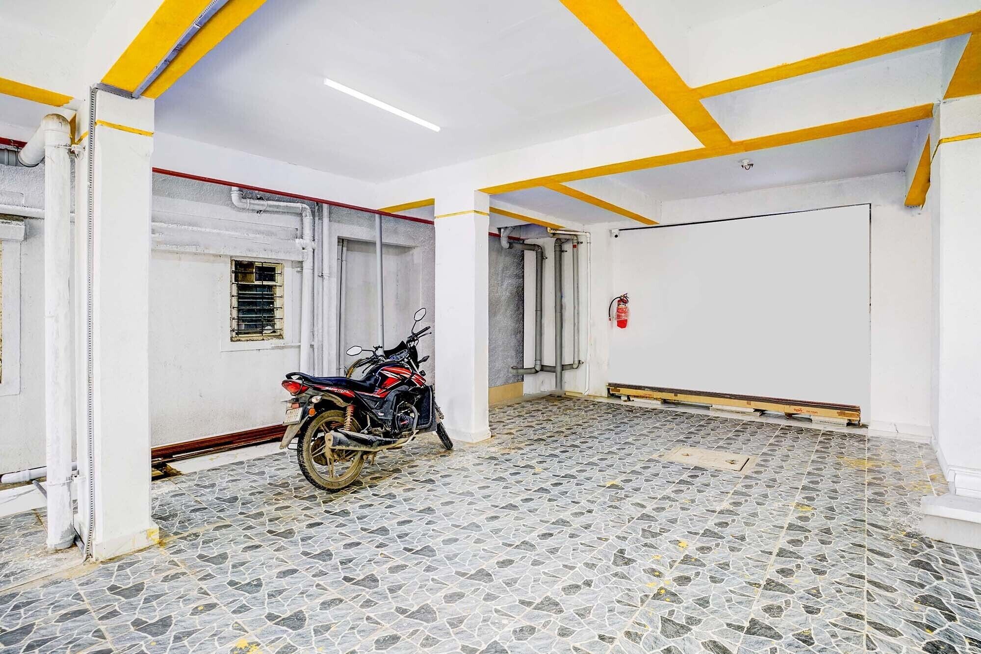 A room with a motorcycle, tiled floor, white walls, and yellow ceiling beams.