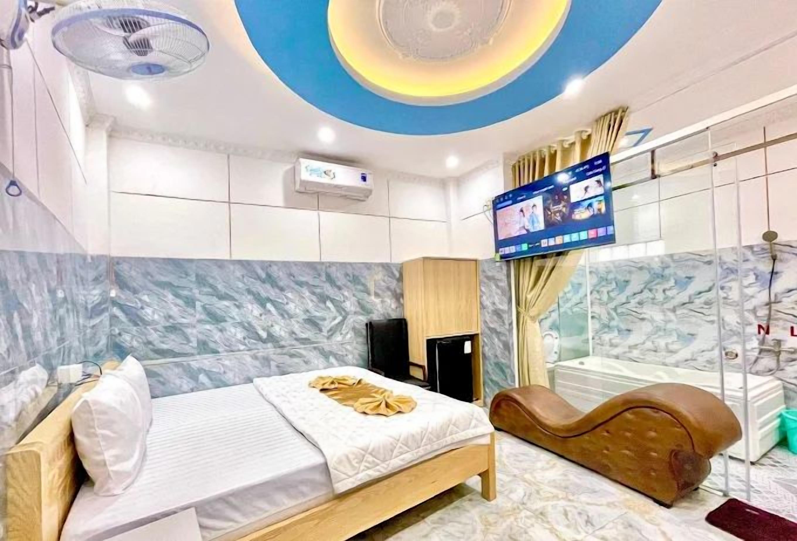 Ein modernes Hotelzimmer mit einem Bett, einem Massagesessel, einem Fernseher und einer Marmorwand.