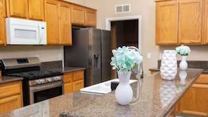 A kitchen with wooden cabinets, a stainless steel refrigerator, a microwave, a stove, and granite countertops. - Delightful home 5 Bedrooms , 2 Bath and 2 living rooms  (Bakersfield)