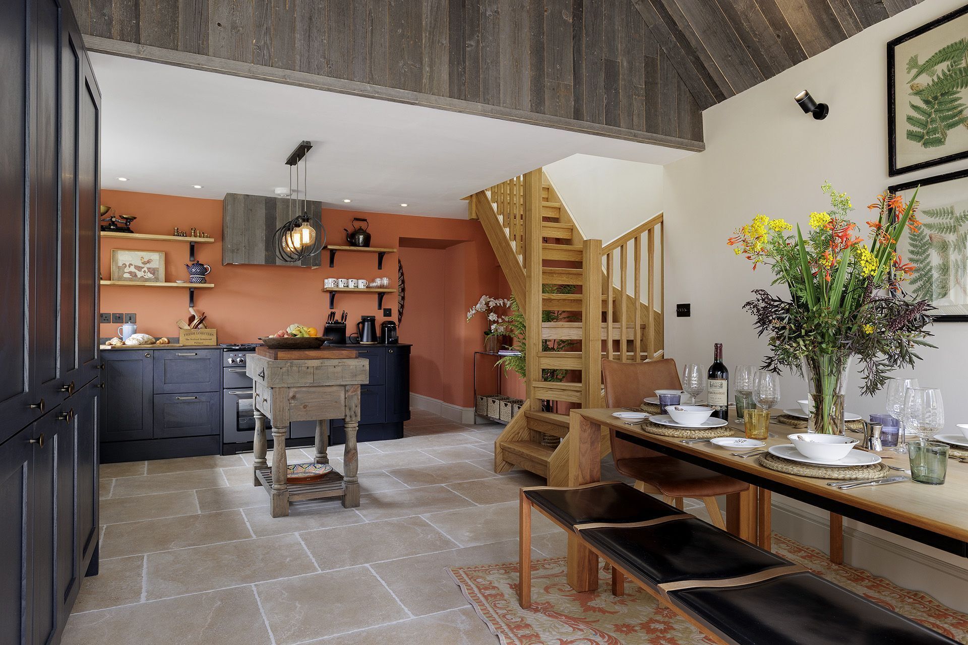 A kitchen with dark cabinets, a wooden island, and a dining area with a table set for four.