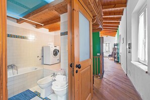 Een badkamer met een wasmachine, een bad en een toilet.