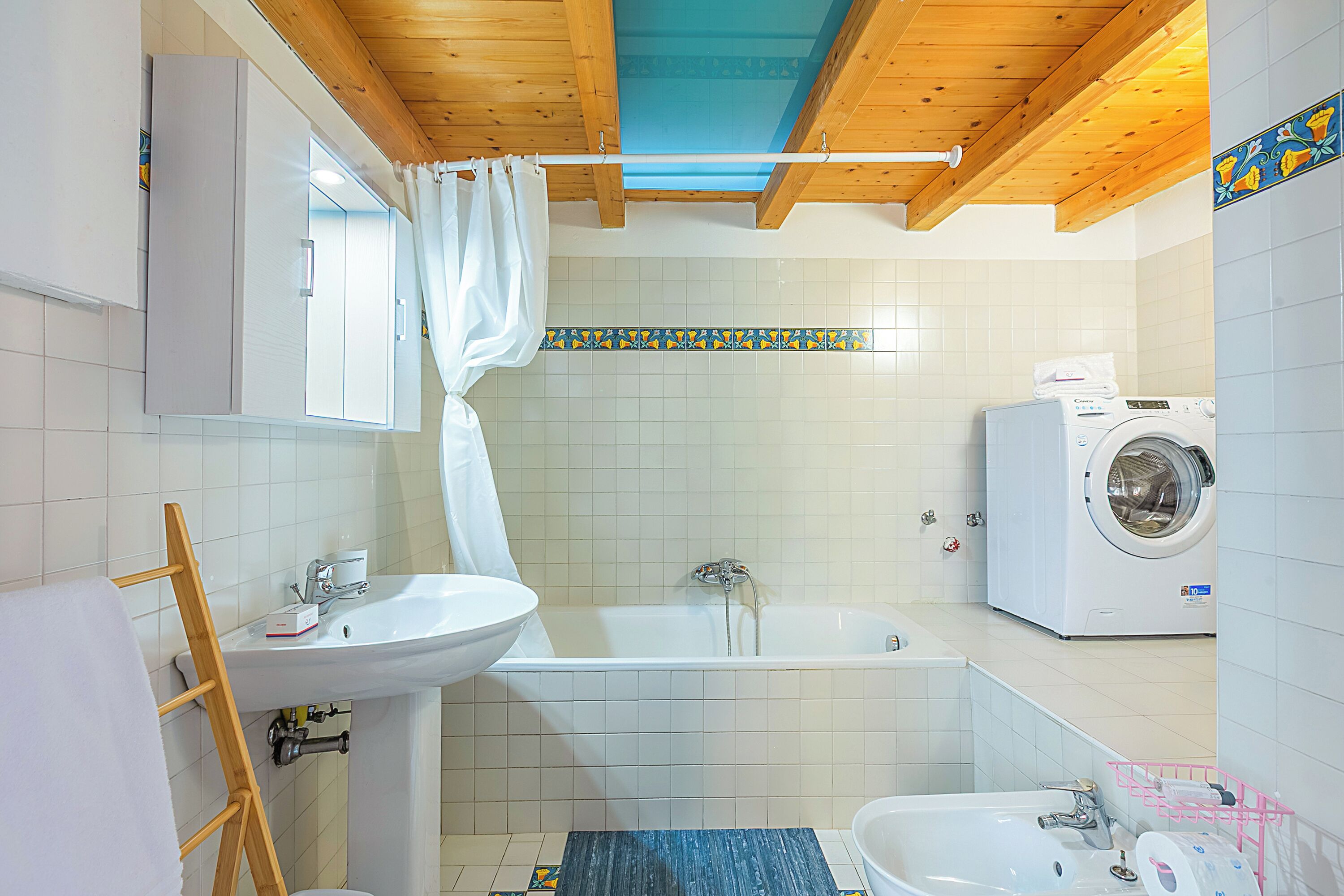 A modern bathroom with a sink, bathtub, and washing machine.