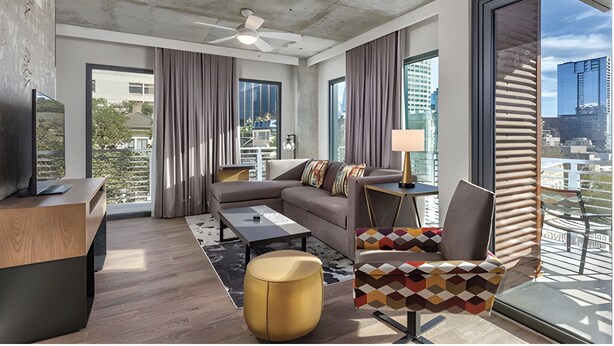 A modern living room with a sofa, coffee table, and a patterned armchair. - Luxurious 2BR Presidential Suite - Great Views Rooftop Pool! Sept 7 - 11, 2025. (Austin)
