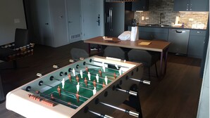 A modern kitchen with a foosball table, a dining table, and a kitchen island. - Luxurious 2BR Presidential Suite - Great Views Rooftop Pool! Sept 7 - 11, 2025. (Austin)