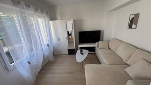 En moderne stue med en beige sofa, et fladskærms-tv og et hvidt sofabord.