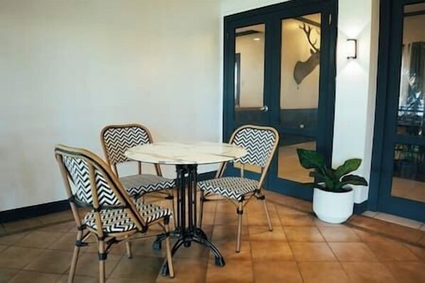 Un comedor con una mesa redonda y cuatro sillas, una planta en maceta y una puerta decorada con un venado.