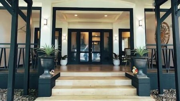 Entrada de hotel con una escalera que lleva a una puerta oscura, flanqueada por dos macetas.